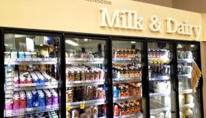 一张杂货店里装满牛奶和奶油产品的冰箱的照片。