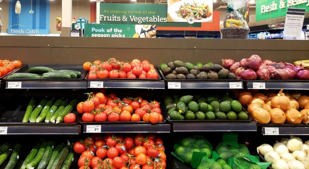 五颜六色的杂货店显示蔬菜，包括黄色和红洋葱，西红柿，黄瓜。