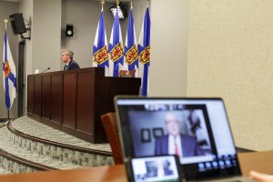 新冠疫情简报室，蒂姆·休斯顿总理坐在桌子前，罗伯特·斯特朗医生正在放大虚拟电话