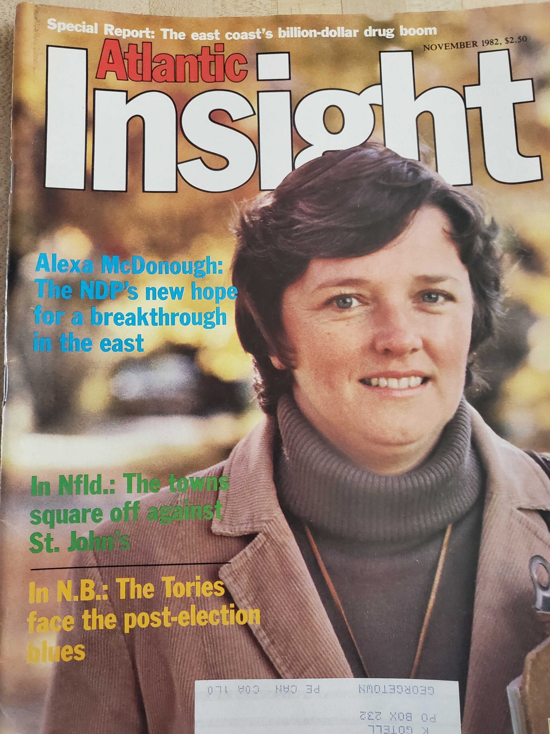 一本杂志的封面上是一位30多岁的白人女性，棕色短发向一边分开。她穿着高领毛衣和夹克。杂志名称是《大西洋洞察》