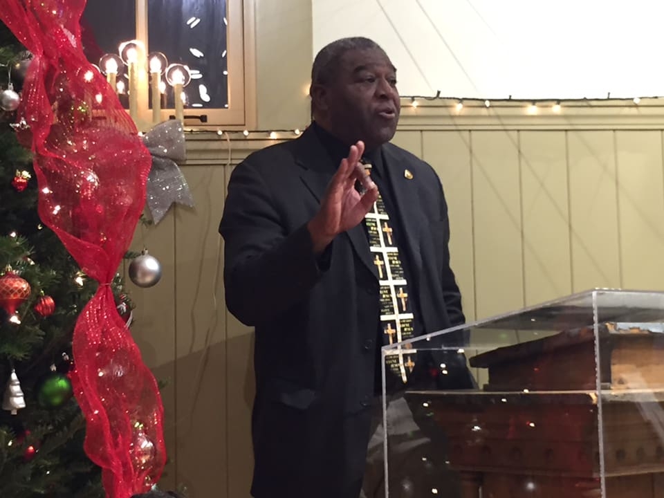 一个穿着深色西装外套的黑人在讲台上讲话