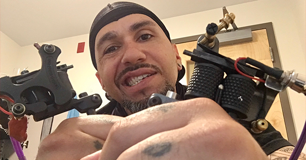 一个戴着黑色波浪帽的黑人拿着纹身枪的特写镜头