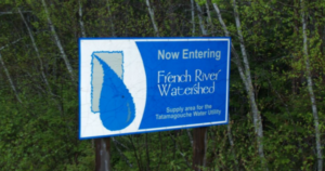 256号公路上被树木环绕的蓝白标志，上面写着“现在进入法国河流域，塔塔马古切水务公司供应区域”。