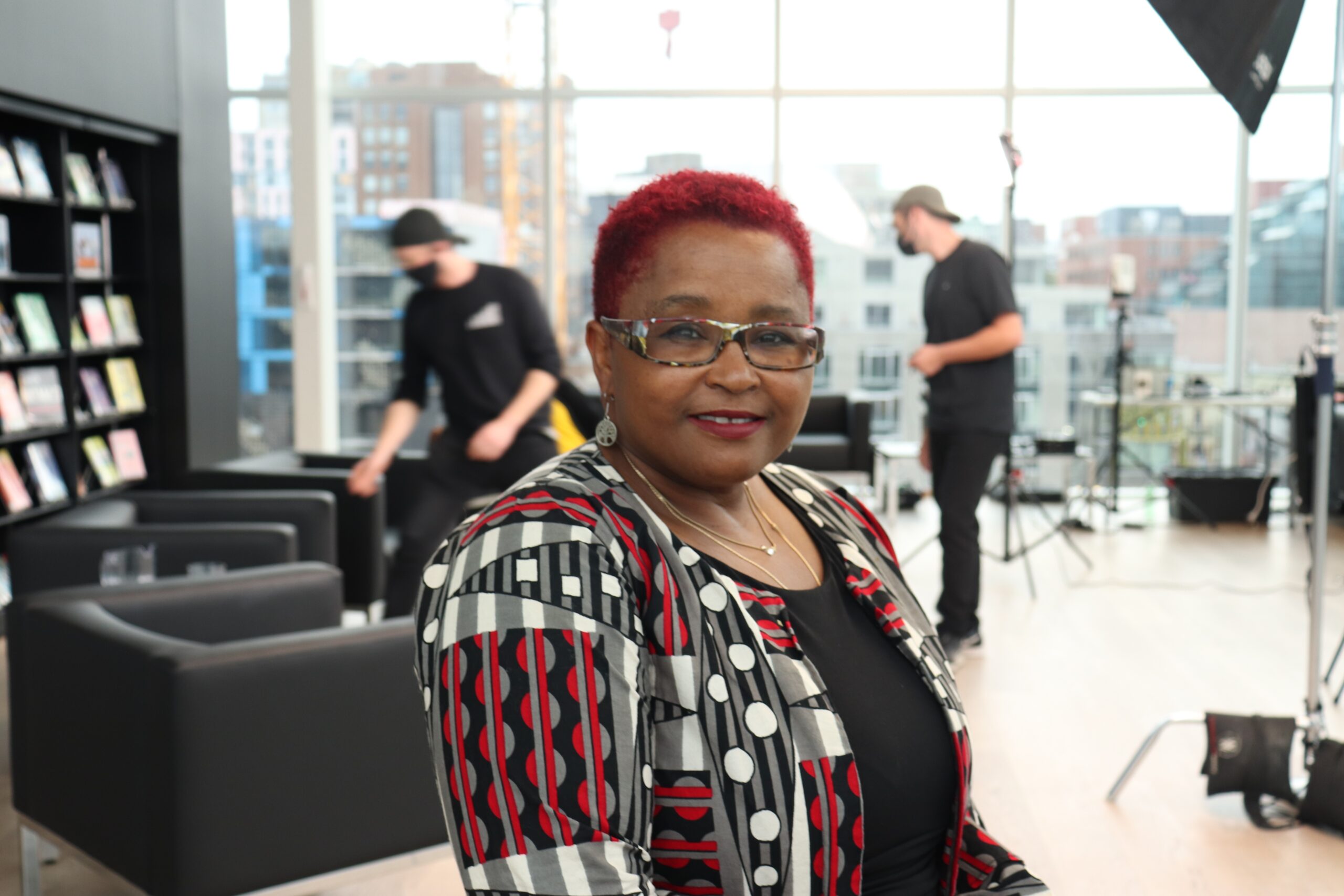 红头发的黑人女士与摄制组合影，背景中哈利法克斯的天际线模糊了。