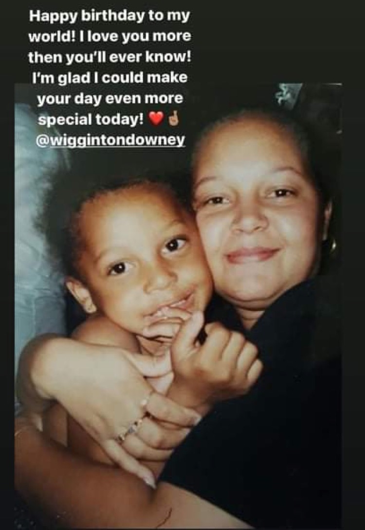 在一张老照片中，一个黑人小孩被他的黑人母亲拥抱，他们对着镜头微笑