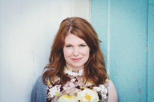 一个留着红色长发的年轻女子手里拿着一束花。