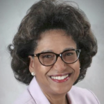 莎朗·戴维斯-默多克，一位黑人女性，在摄影棚里穿着一件可爱的淡粉色夹克微笑