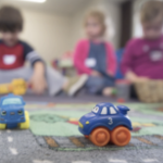 孩子们在垫子上玩塑料玩具车