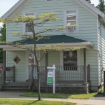 城市街道上挂着出售标志的绿色房子