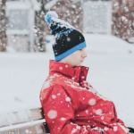 一个穿着红色冬衣的男人坐在雪地里的公园长凳上