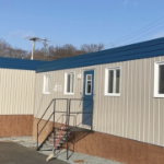 一个模块化的住房单元，米色的蓝色屋顶和白色的窗户装饰。