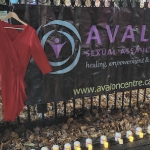 栅栏上挂着一件红裙子，还有阿瓦隆性侵犯中心的标志