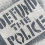 人行道上喷着一个写着“撤资警察”的黑色模板