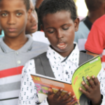 一个黑人小男孩大声朗读一本书