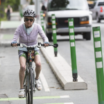 一位白发苍发的老太太骑着自行车在一条受保护的自行车道上