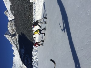 三个滑冰者在冰封的露易丝湖的阳光下打曲棍球。背景是雪山