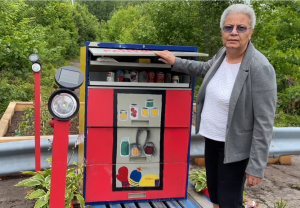 一位妇女站在油漆鲜艳的食品储藏室旁边。