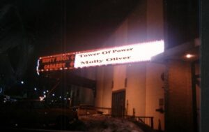 A sign above a bar that says Tower of Power and Molly Oliver