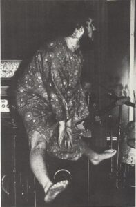 A black and white photo of a man on stage jumping