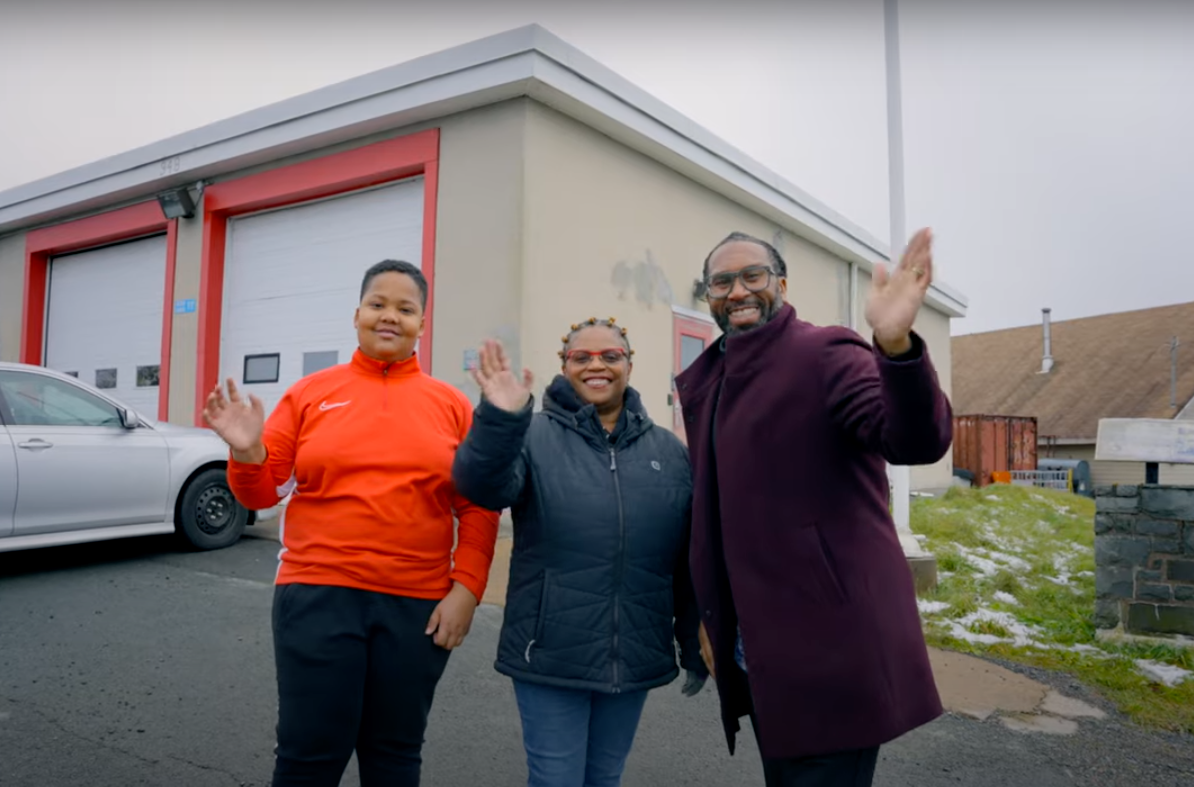 三人挥手，因为他们站在有车库门的消防大厅前面。