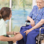 一位年轻的CCA帮助一位坐轮椅的老妇人