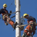 两名NS电力公司的工人站在一根杆子上