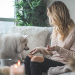 一名年轻白妇女和她的白色狗坐有白色坐垫的沙发