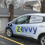 一辆电动车，在司机侧有一个图形读书“Zevvy”。