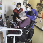 两名妇女扶着一位老太太坐轮椅