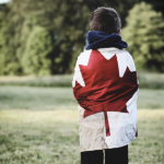 一个身穿加拿大国旗的白人小孩站在田野里