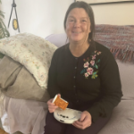 一名白人女子坐在沙发上，手里拿着一瓶药，手里拿着一个白色圆盘形状的小工具来阅读标签