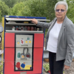 A woman stands beside a brightly painted community pantry