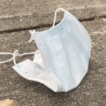 a disposable mask discarded on a sidewalk