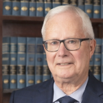 一个满头白发的白人站在书架前