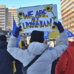 一名抗议者举着一个标语，上面写着“我们都是乌克兰人”