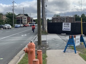 照片上的一个建筑工地显示，一条人行道被封锁，一名行人在路上行走。