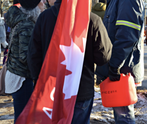 A man holds a gas receptacle with the word 'freedom' written on it