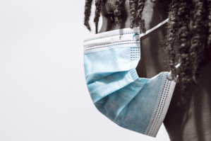 一个人在白色背景下戴着一个蓝色的外科口罩，盯着左边。