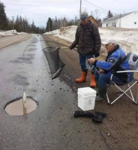 两个人在路上的一个坑洞里假装用冰钓鱼