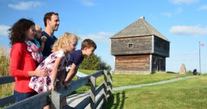 一家人站在一座古老的木制堡垒附近的木板路上