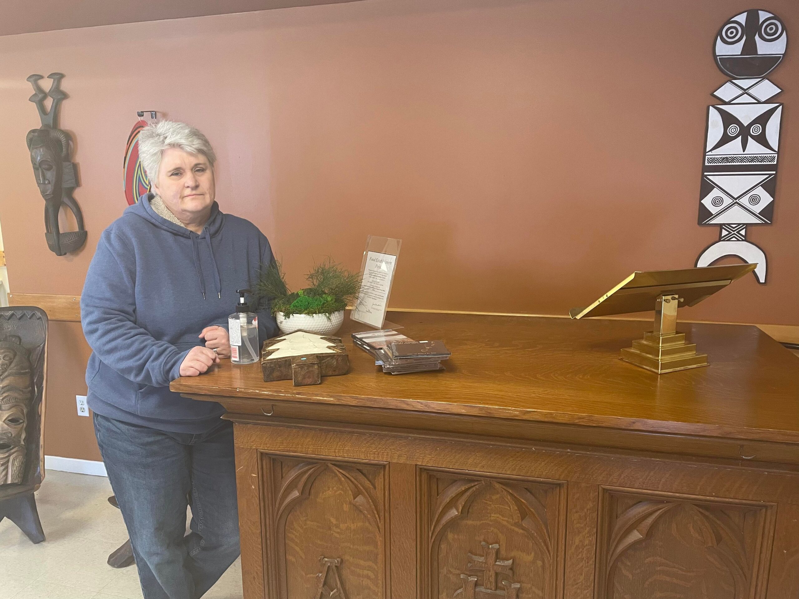 一个留着白色短发的女人站在一个大木坛旁