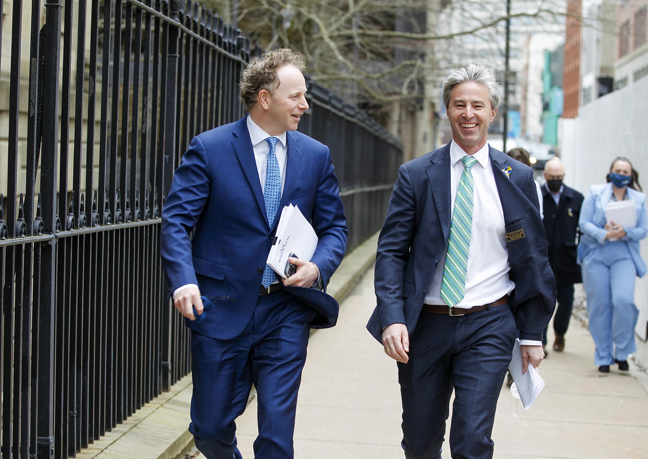 两个穿西装的男人走在哈利法克斯市中心的街道上。