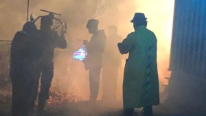 喜怒无常的雾图像。框架中有五个阴暗的数字。一个人穿着长型外套和老式的帽子。相机和声音设备可见。