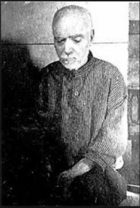 一张身穿条纹服装的男子的黑白照片。他向下看