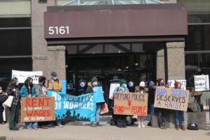 A group of protestors with signs in front of a building
