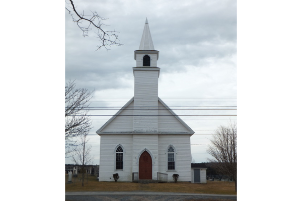 在一个阴云密布的灰蒙蒙的日子里，一座古老的白色教堂，旁边是一座墓地。