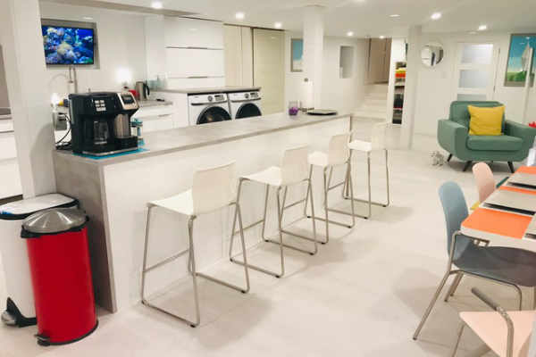 以前的教堂地下室最近翻新了一个厨房岛台，白色的凳子，一把绿色的大椅子和餐桌。