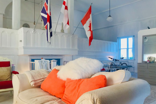 客厅里有浅色的沙发和橙色的枕头。