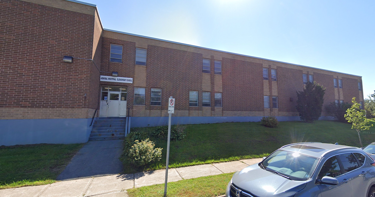 a brick school building with a car parked out front.