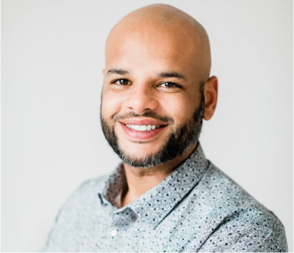 有胡子的秃头黑人在灰色毛线衣微笑微笑。灰色背景。